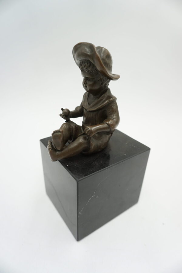 FIGURA Z BRĄZU SIEDZĄCY CHŁOPCZYK NA PODSTAWIE Z KAMIENIA